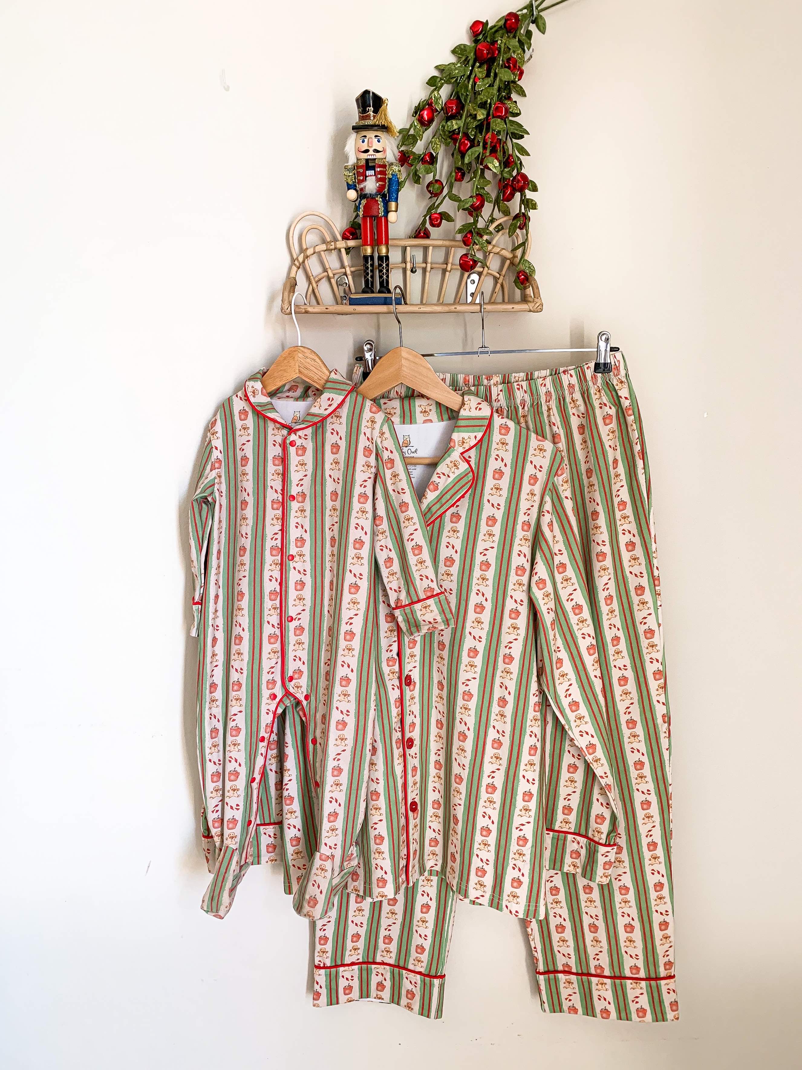 pyjamas hanging from a rattan shelf for kids and adults. the pyjama pattern ids red and green stripes with images of hot chocolate, candy canes and gingerbread.