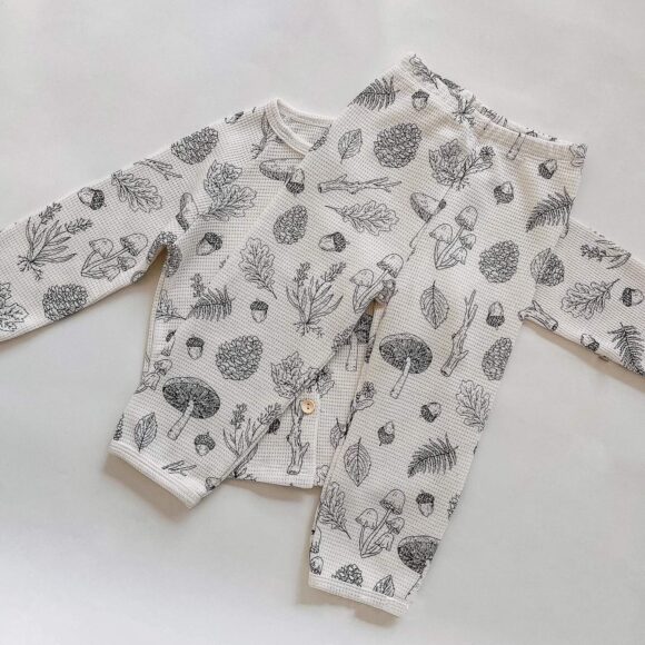 image shows a set of waffle cotton loungewear clothing for toddlers and young children. The pants are on top of the sweatshirt and they both showcase woodland pattern.