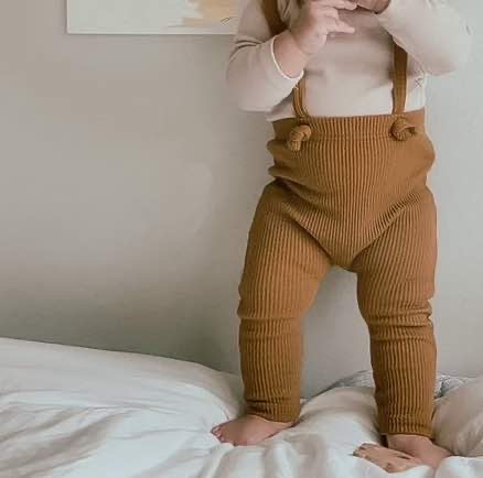 Toddler stood up and showcasing what ribbed cotton suspenders in khaki look like when a toddler is wearing them.