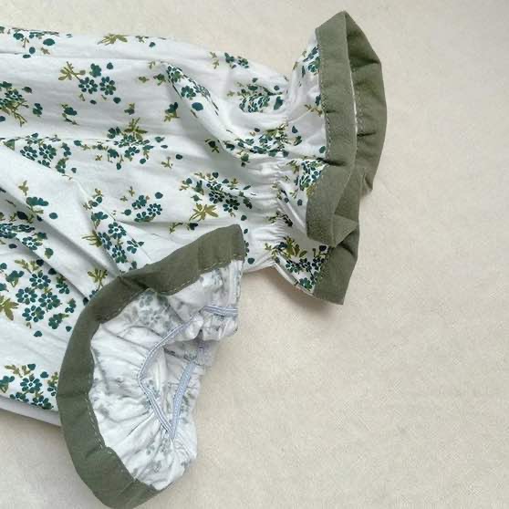 The sleeve and cuff of a girls vintage romper. The cuff is elasticated and picture shoes the thickness of the cotton and green trim of sleeve.