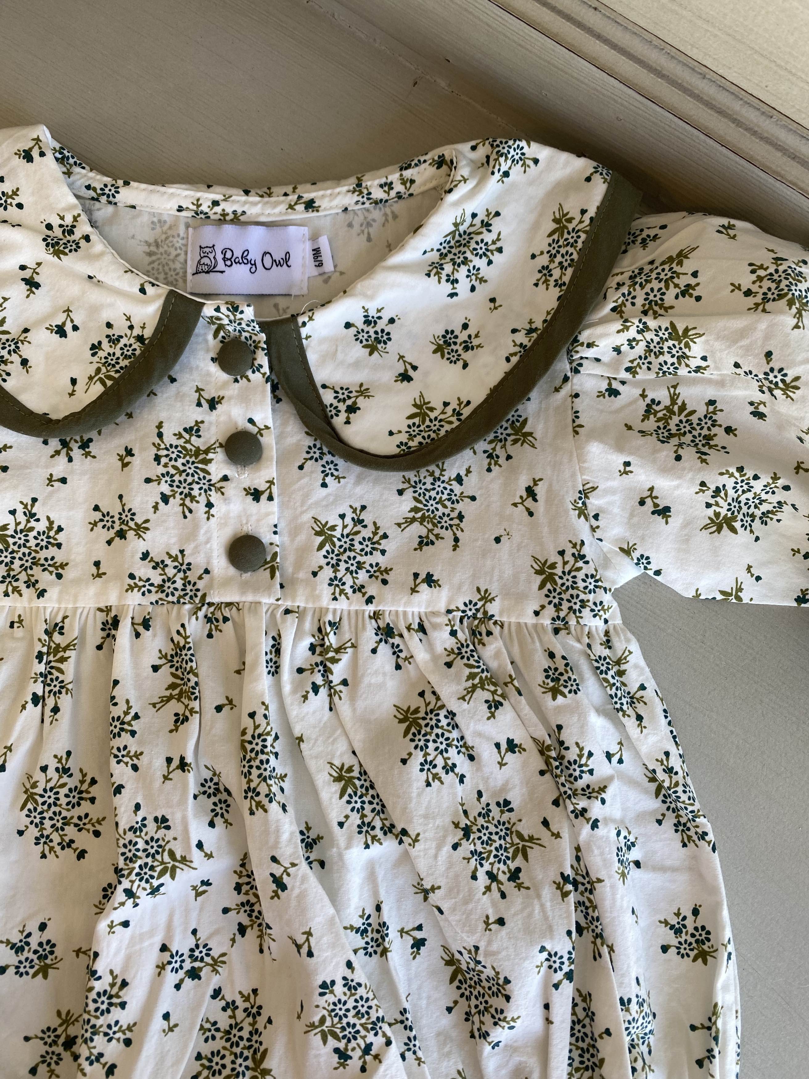 Close up picture of floral vintage romper. Picture shows Peter Pan collar and its contrast green piping and three green buttons at neckline.