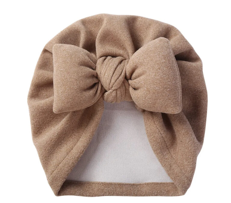 baby cotton turban on display with white background. big bow at front in a greige colour.