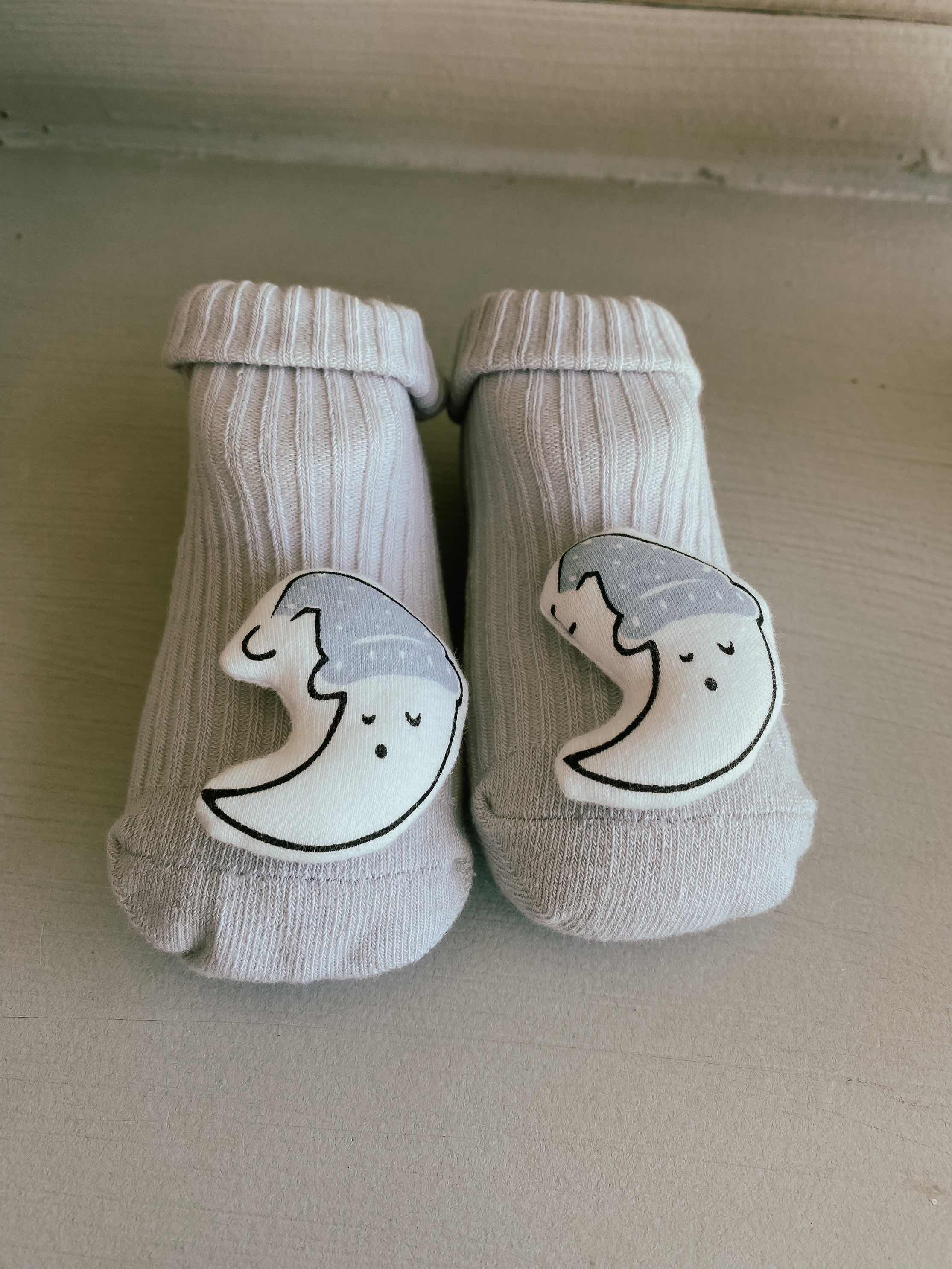 Display of baby sock slippers with a moon image on toes