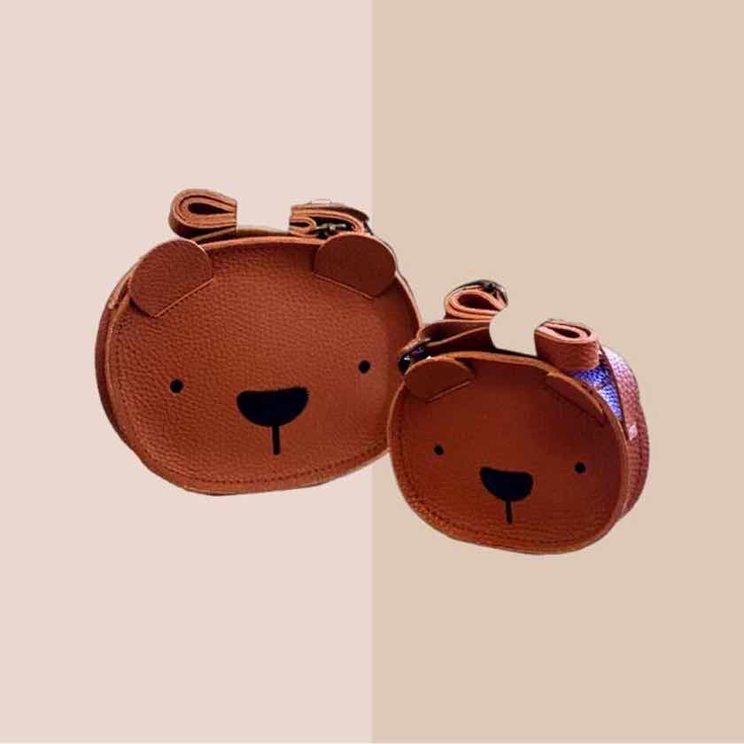 Two brown bear coin purses on a beige and khaki background. one is smaller than the other and they have been placed next to each other.