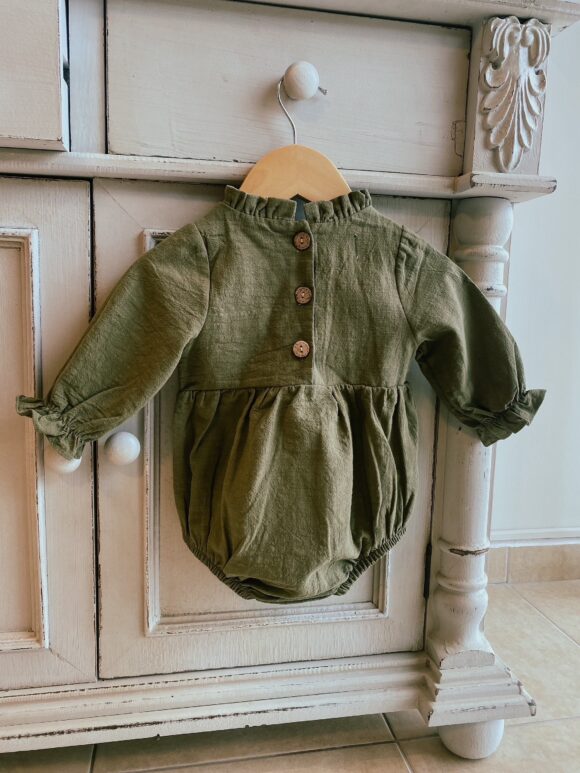 picture shows back of girls green linen romper. frilly collar and wood buttons at the back.