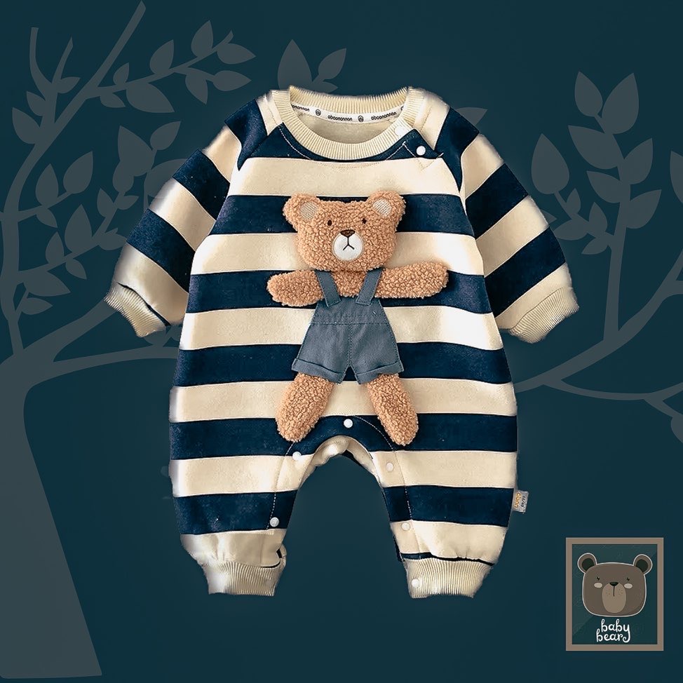 Baby full body romper in navy and cream stripe has been placed on a dark, grey blue background. Laid down flat to show style of the bodysuit which is thick and closes with metal fasteners at the bottom. Huge teddy bear wearing dungarees has been sewn to the front of the whole bodysuit romper.