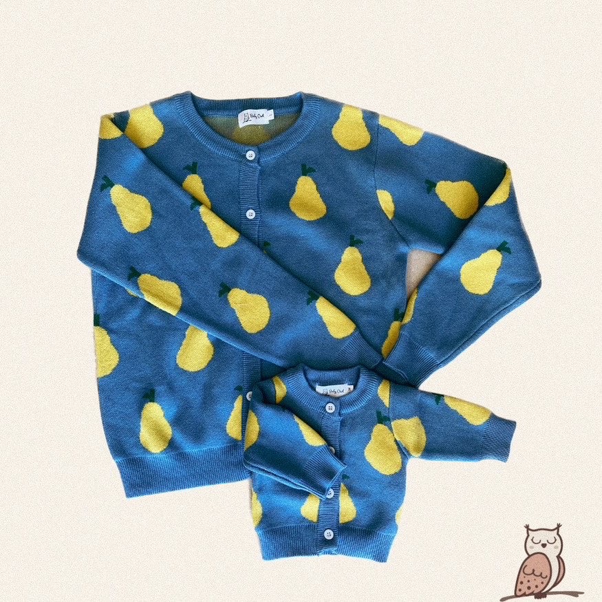 two cardigans are displayed laid down flat on a plain background. There is a mom cardigan and a small baby cardigan. The cardigans are blue with yellow pears on them. Button front