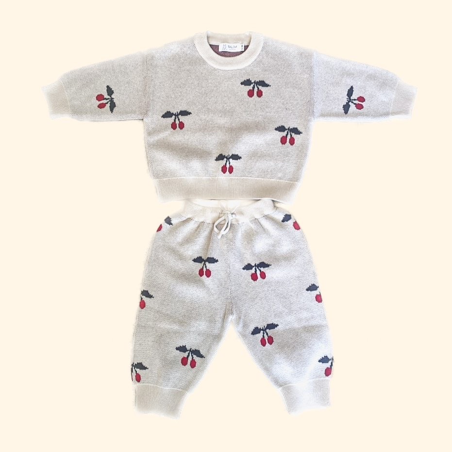 cherry sweatshirt and jogging pants set. Cream jacquard knitted fabric with cherry print on it. the top and bottoms are matching and come as a set they are laid out in such a way to display the cut of the fabric, shape of the clothing and style, plus the pattern.