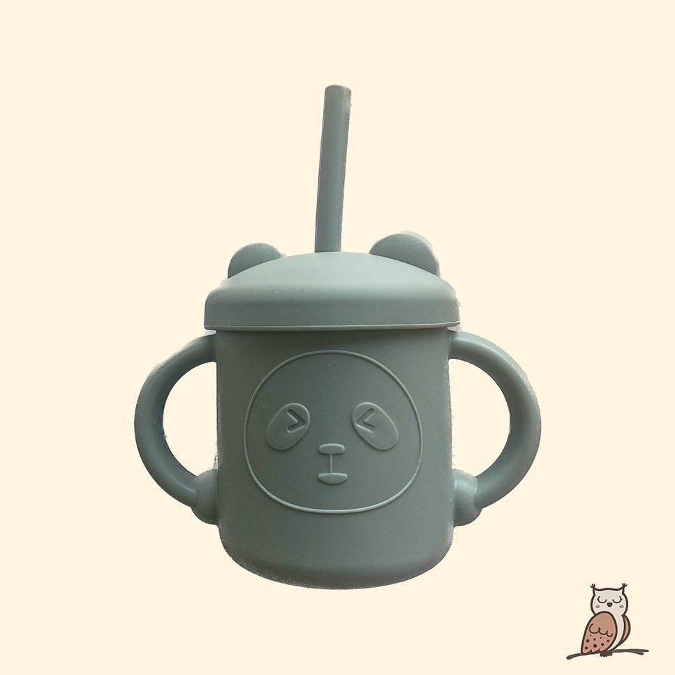 silicone sip cup. baby and toddler first bottle or cup. the cup is sat uprights and has a straw inside. the top of the cup has little ears and there are two ergonomic and easy to grip handles on each side of the cup. sage green and made from silicone. all one colour.