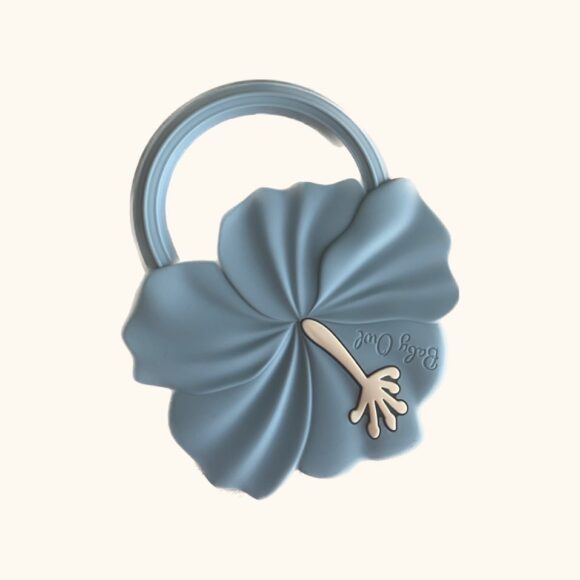 Baby teething ring in shape of a flower. Round handle attached to flower. flower is in dusty blue colour and has a white flower in the middle.