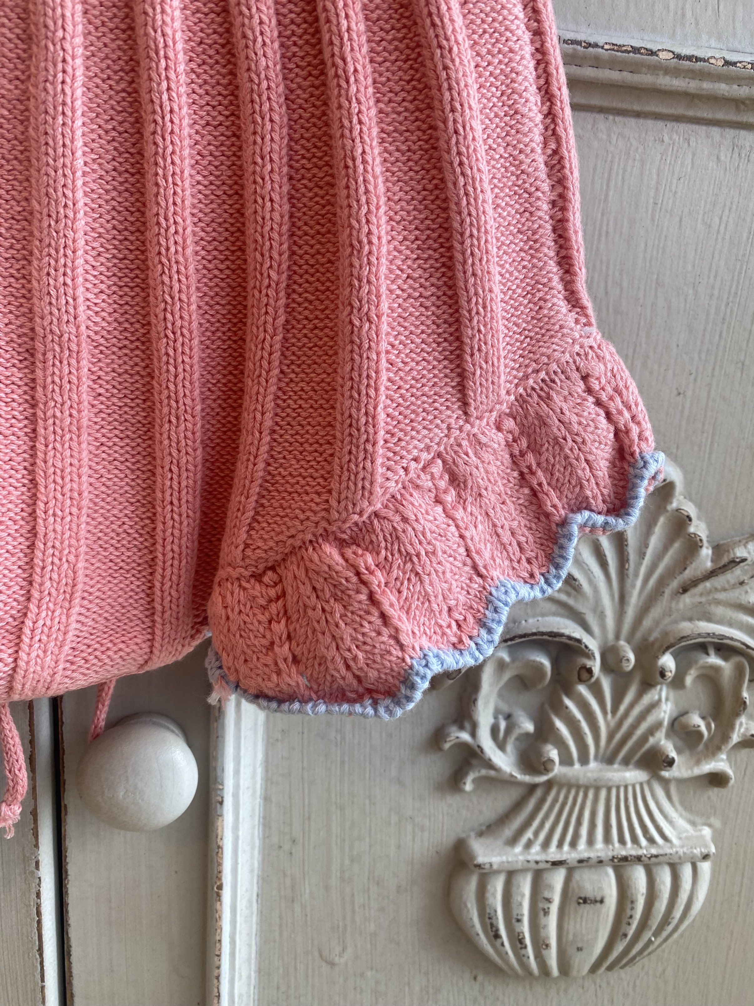close up of a knitted baby and toddler bloomer or skirt. Shows pink knitted bloomer with a dainty, frilly edge with blue edge.