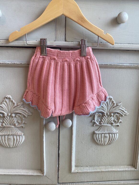 toddler girls knitted bloomers in warm pink. frilly edges with retro style and blue trim at the edge of the frill.