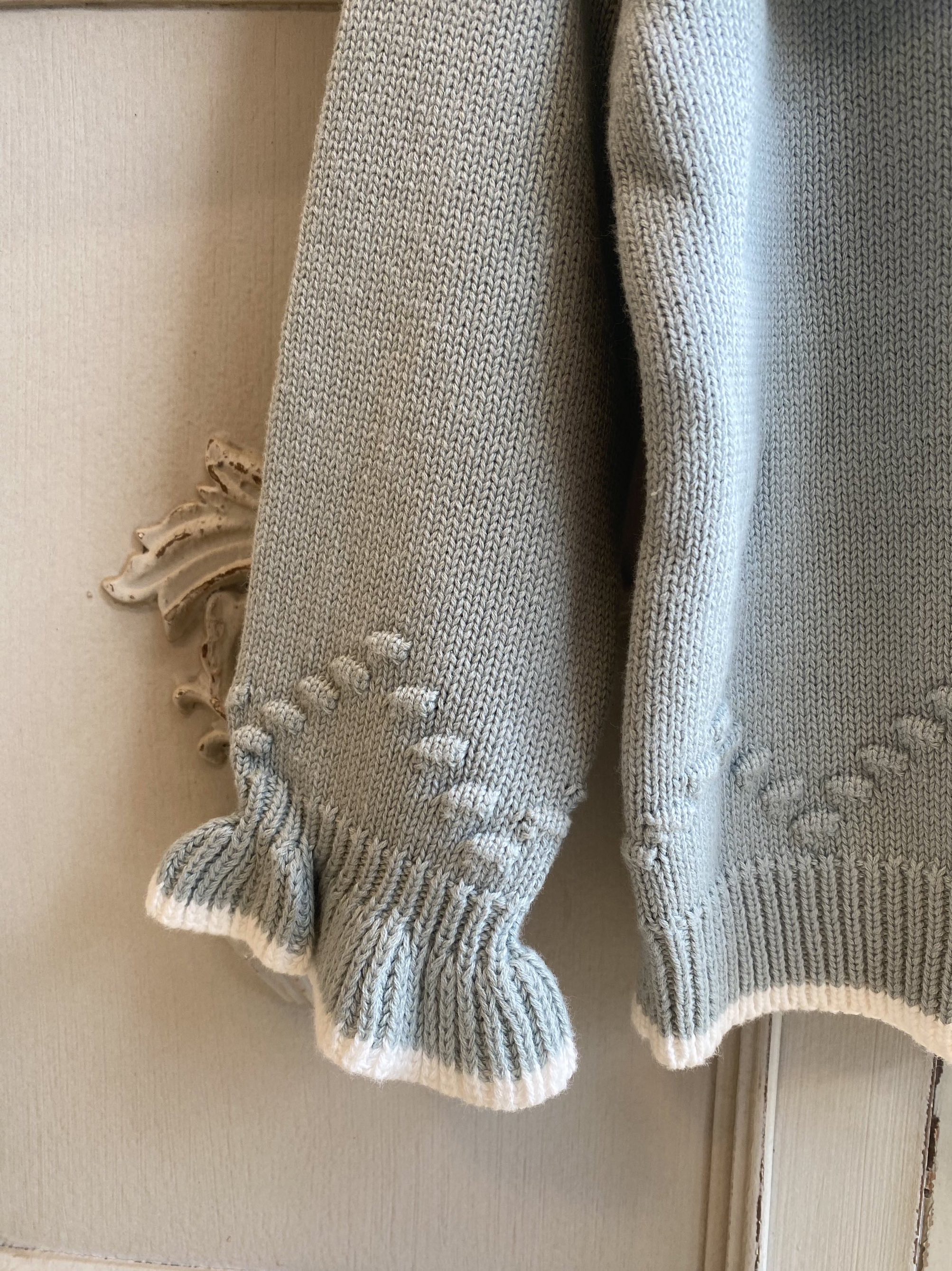 Close up of a girls knitwear jumper. Picture shows the stitching detail of the cotton and also the frilly cuff.